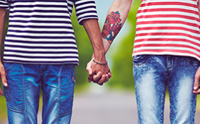 Two people hold hands while standing in the middle of the street.