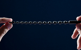 Two hands holding up a black sounding rod.