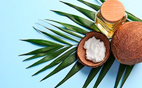Coconut oil for private parts next to a coconut on a leaf.
