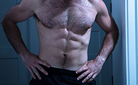 A shirtless 40 year-old male contemplates body changes.