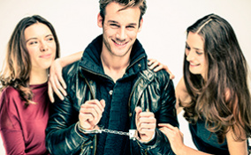 thumbA man is smiling and handcuffed as he stands between two women.