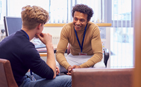 A PrEP counselor smiles as he talks with a young man in his office.