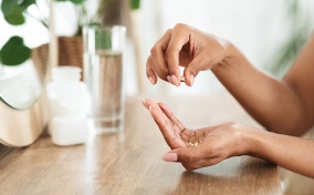 A woman's hands holding vitamins that help with vaginal dryness.