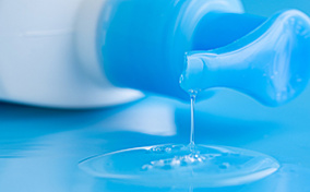 Blue-lube-bottle-lying-down-with-lube-leaking-onto-a-blue-surface