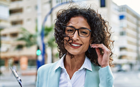 A-smiling-woman-in-glasses-touches-her-hair