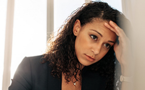 A stressed woman leans her head into her hand.