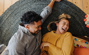 A-couple-laughs-while-laying-together-on-floor
