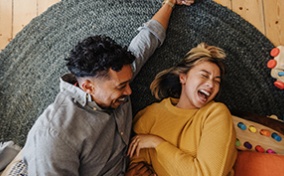 A-couple-laughs-while-laying-together-on-floor