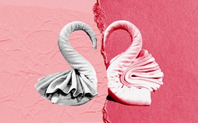 Two towels formed into half a heart break apart against a multi-shaded pink background.