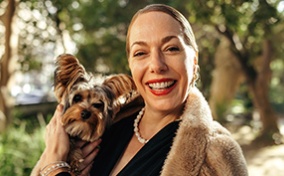 A single woman smiles holding her dog.