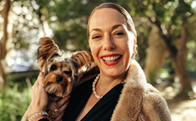 A single woman smiles holding her dog.