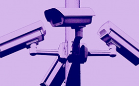 Four security cameras face different directions with a purple filter over the photo.