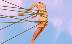 An arched, headless female body against a blue and pink sunset is held back by threads. 