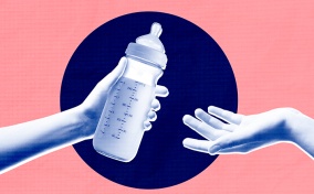 One arm is reaching out to hand a bottle of breast milk to another.