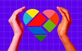 Two hands surround geometric pieces that form a heart.