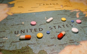 Pills are scattered over a map of the US.