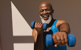 A man in workout gear exercises with weights in his hands.