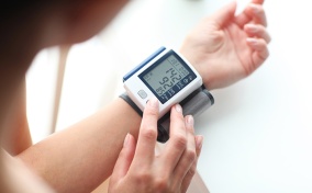 A pregnant woman uses a self-monitoring blood pressure gadget.