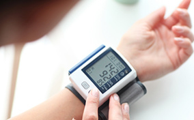 A pregnant woman uses a self-monitoring blood pressure gadget.