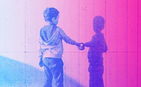 A little boy reaches out to touch his shadow on a pink wall. 