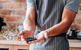 A man holds blueberries between two cupped hands.