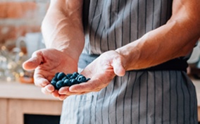 A man holds blueberries between two cupped hands.