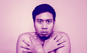 A man covers his body with his arms looking scared.