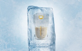 A bag of breast milk sits is frozen inside of an large block of ice.