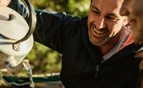 A man pours hot water from a kettle into a mug for green tea.