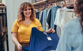 A sales associate shows clothing to a woman. 