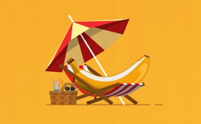A banana lays in a beach chair underneath an umbrella and next to a picnic basket.