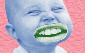 A squinting baby has an adult mouth with teeth photoshopped over its mouth.