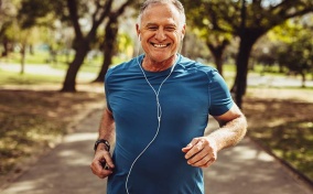 A man smiles while jogging and listening to music.