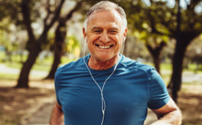 A man smiles while jogging and listening to music.