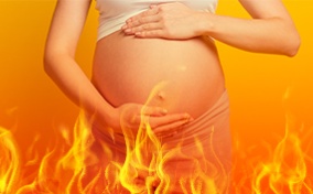 A pregnant woman holds her belly against an orange background with fire flames below.