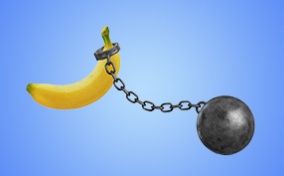 A ball and chain is linked on the end of a banana against a blue background.