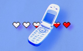 An old flip cellphone is open with a line of white hearts behind it that are filling up with red.