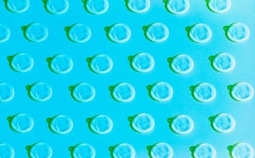 A pattern of white condoms repeat against a blue background.