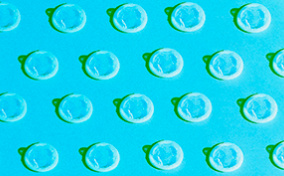 A pattern of white condoms repeat against a blue background.