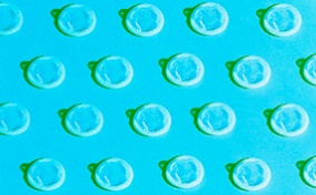 A pattern of white condoms repeat against a blue background.