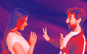 A woman looks at her partner with hands together and smiling while he looks surprised.