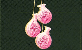 Three pink yoni pearls dangle together against a textured dark green background.