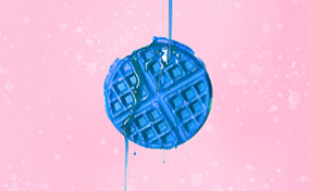 A blue waffle is against a pink background with blue syrup pouring down over it.