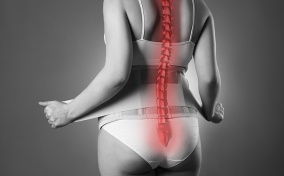 The back of a pregnant woman is shown in black and white with her spine glowing red.