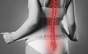 The back of a pregnant woman is shown in black and white with her spine glowing red.