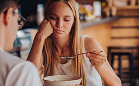 A woman looks negatively at her food while on a date.