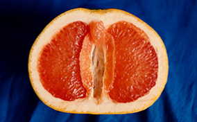 Half of a grapefruit sits open-faced against a blue cloth.