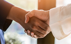 A person with a blue sleeve is shaking hands with someone with a white sleeve.