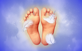 Two feet float in purple misty space with soles facing forward and three feathers brush the skin.