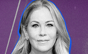 Christina Applegate poses for a camera at an event against a purple background.